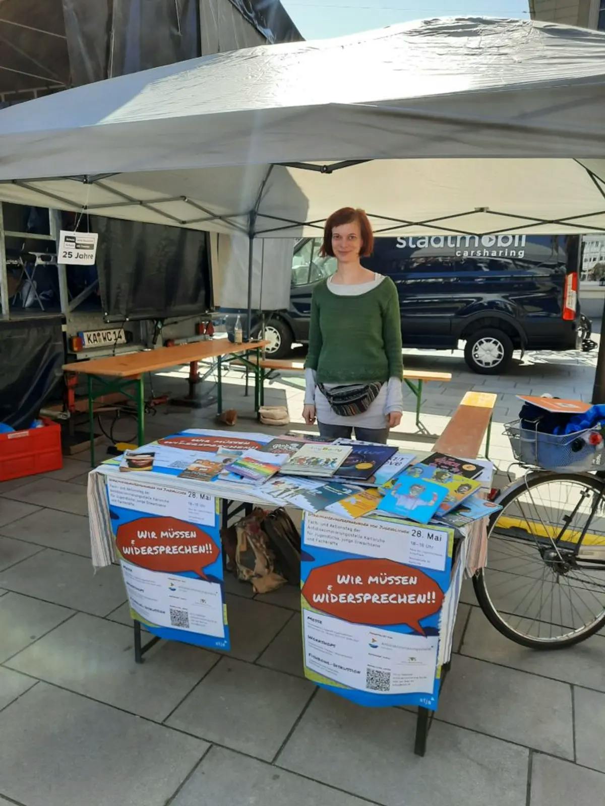 Abgebildet ist unser Stand auf dem Marktplatz mit vielen Broschüren und einer Mitarbeiterin der Antidsikriminierungsstelle Karlsruhe.