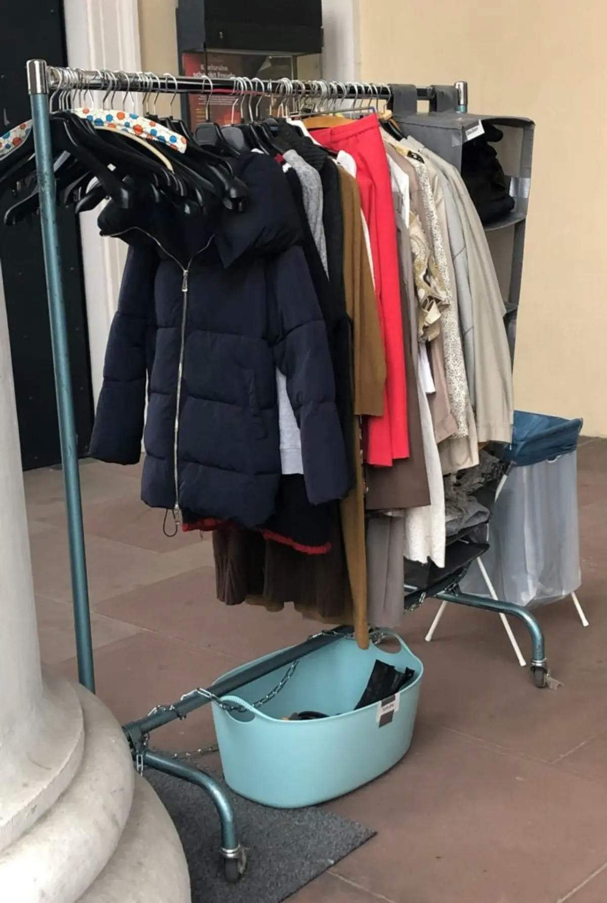 Ein Foto von der öffentliche Kleiderstange und -behälter mit gespendeter Kleidung.