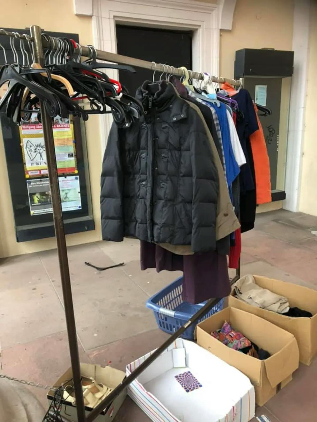 Ein Foto von der öffentliche Kleiderstange und -behälter mit gespendeter Kleidung.